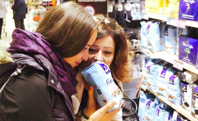 Zwei Frauen halten eine Packung Kaffebohnen in der Hand und riechen daran